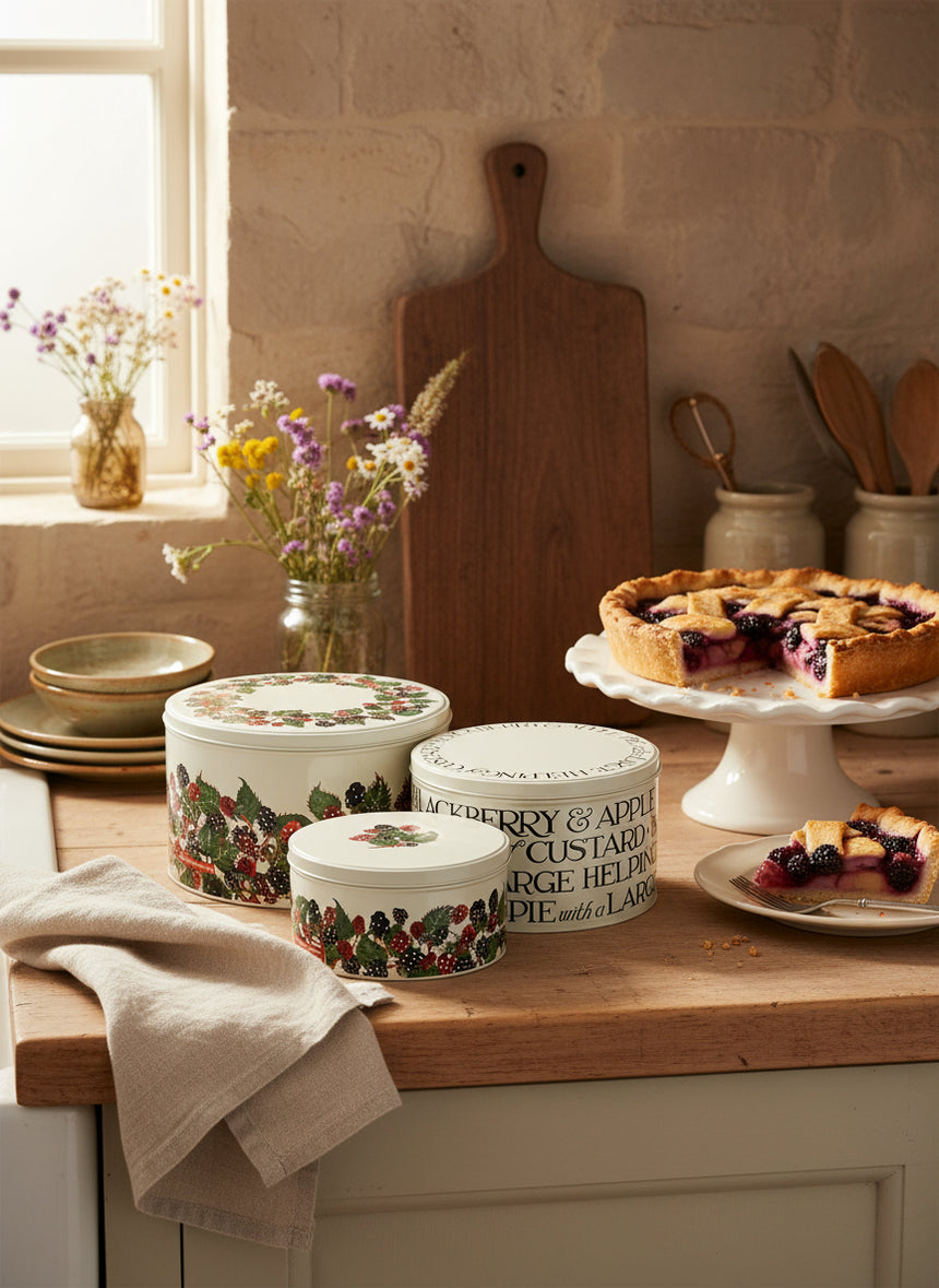 Set of three decorative tins with festive design and text on a white background