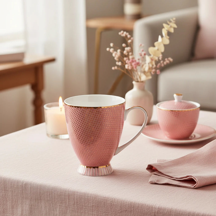Pink mug with gold polka dot pattern on a white background