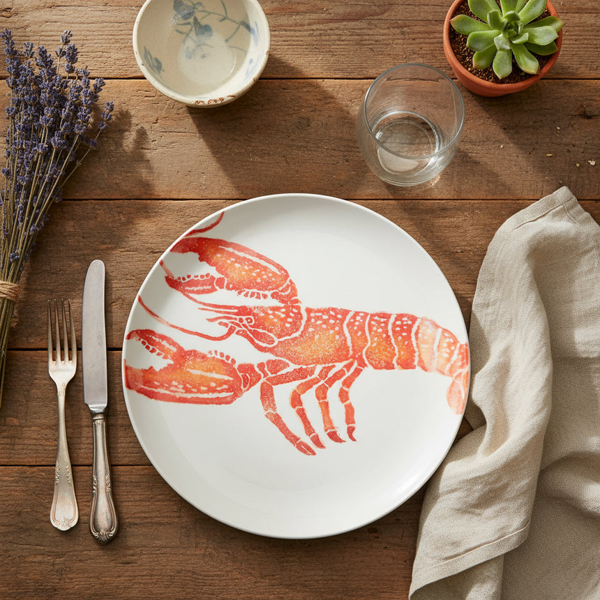 Round white plate with a red lobster design on a white background