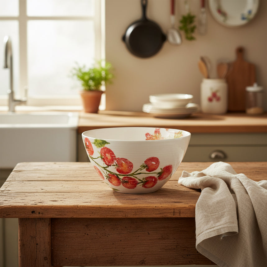 A ceramic salad bowl with hand-printed illustration of cherry tomatoes on the vine and lollo rosso lettuce, primarily in red and green colors.