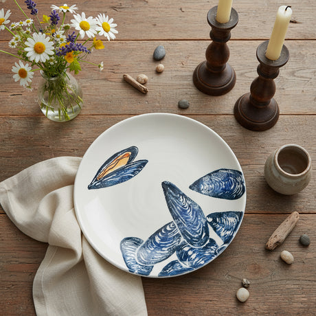 Round ceramic plate with blue mussel shell design on a white background
