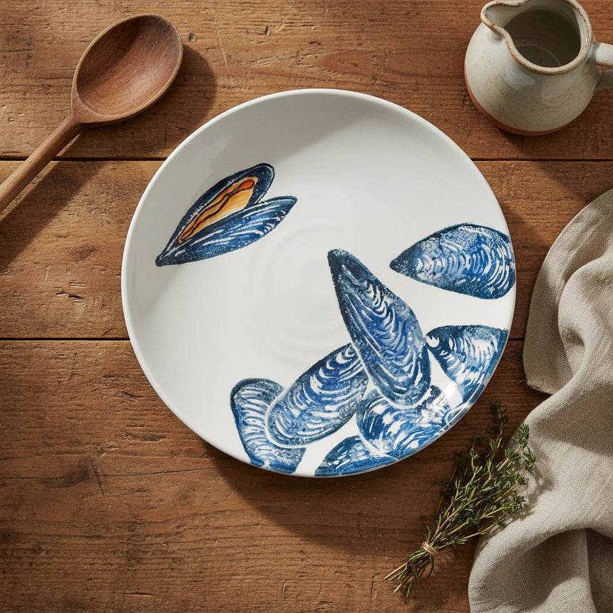 Round ceramic plate with blue mussel shell design on a white background