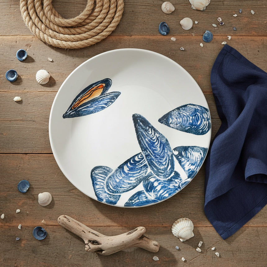Round ceramic plate with blue mussel shell design on a white background