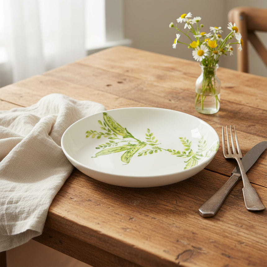 Round ceramic plate with green leaf design on a white background