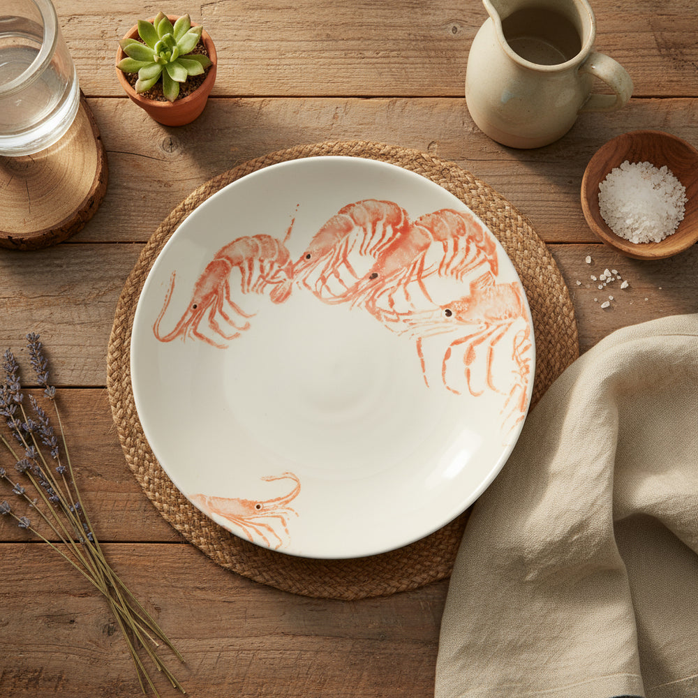 A round earthenware supper bowl with hand-printed illustrations of school prawns in bright orange color.