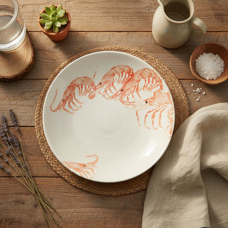 A round earthenware supper bowl with hand-printed illustrations of school prawns in bright orange color.