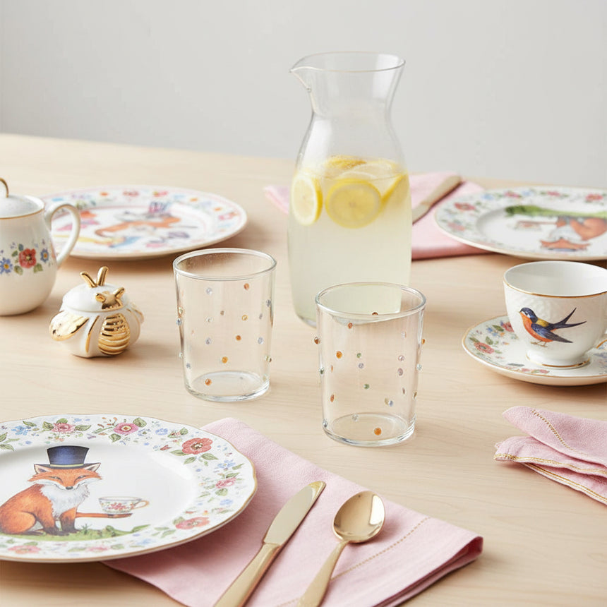 A set of two hand blown textured glass tumblers with a multicolored dot pattern on a white background.