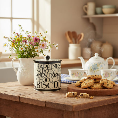A cylindrical stainless steel biscuit barrel with a black toast pattern and text around the middle. The lid has a black handle and the text reads 'HAPPINESS IS A POT OF TEA, A NEW BOOK & A CHOCOLATE BISCUIT'.