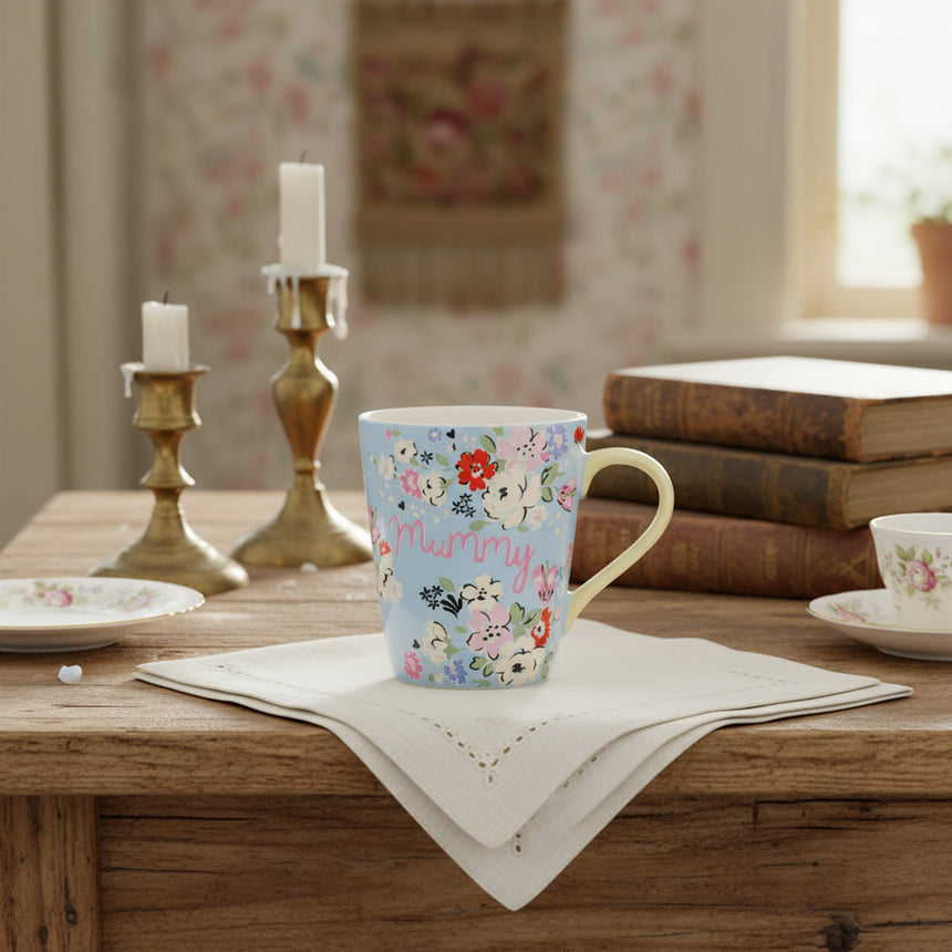 A multicolored floral pattern mug with the word 'mummy' in the center, featuring a contrasting yellow handle.