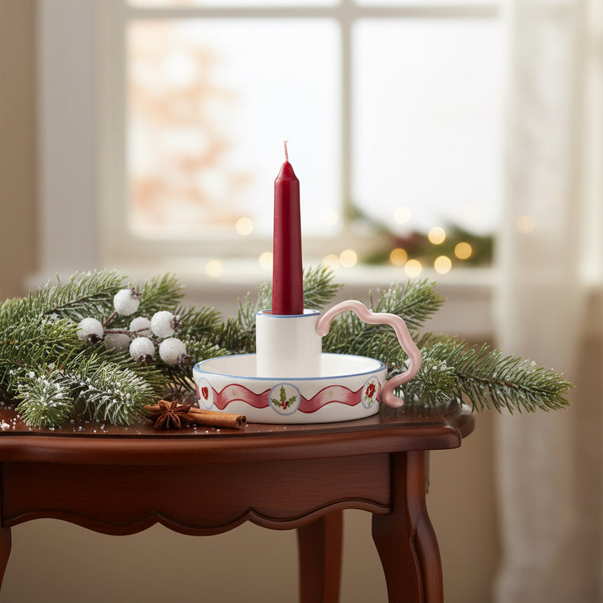 Decorative candle holder dish with floral design and pink handle on a white background