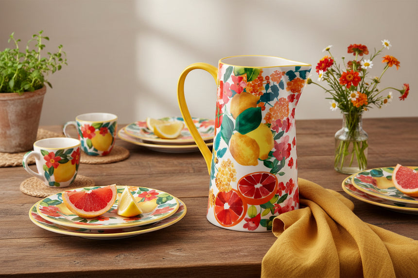 Decorative pitcher with floral and fruit design on a white background