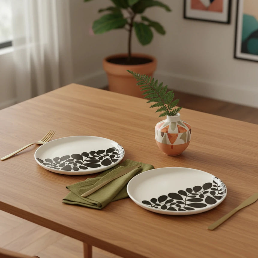 Pair of circular earrings with black leaf pattern on a beige background