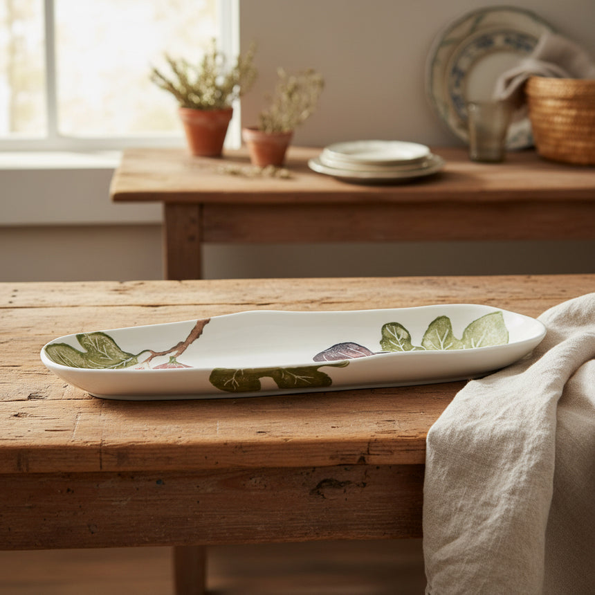 White ceramic platter with green leaf patterns on a white background