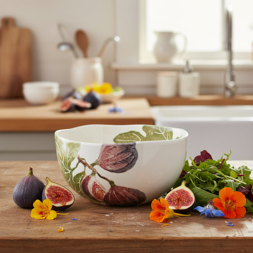 A small, white earthenware salad bowl with a hand-printed illustration of fig fruits around the bottom edge.