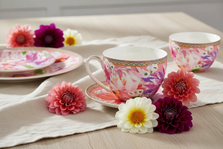 Colorful floral teacup and saucer set on a white background