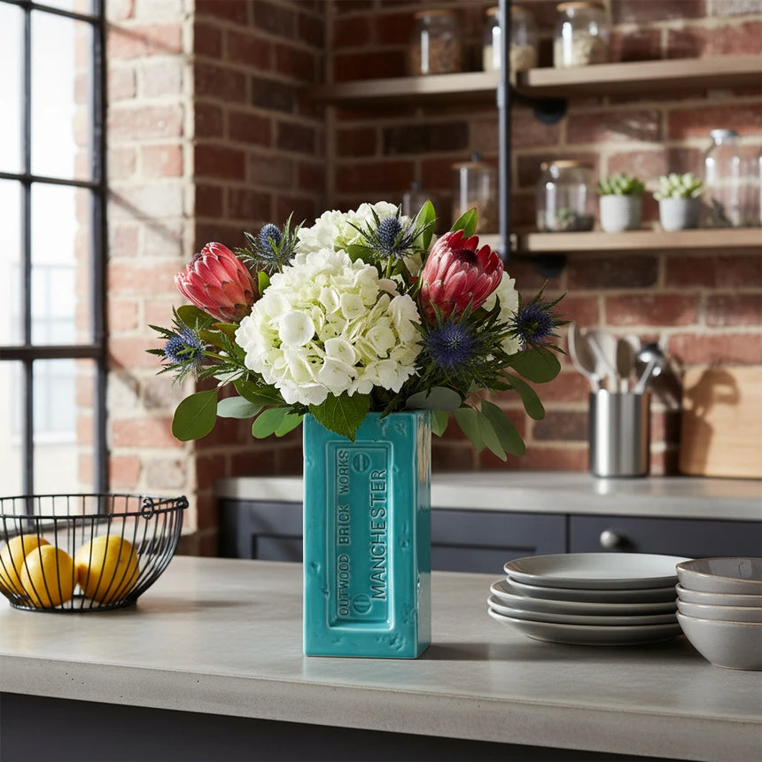 Teal rectangular vase with 'Outwood Brick Works Manchester' branding on a white background