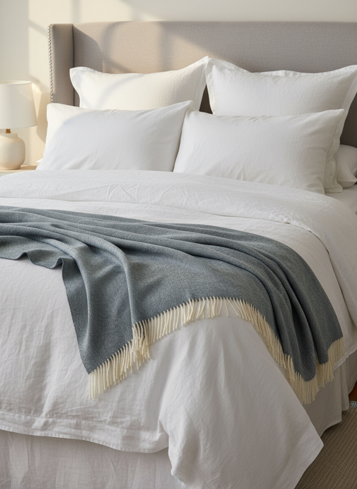 teal blanket with white fringes draped over a beige surface