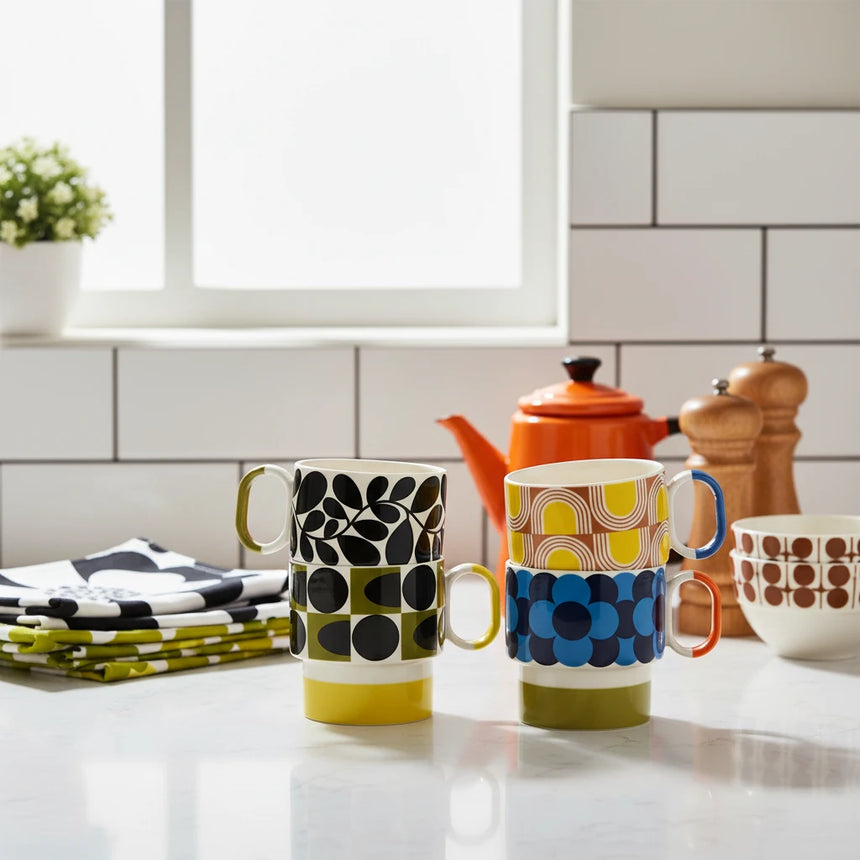 Four colorful mugs with patterned designs on a light beige background