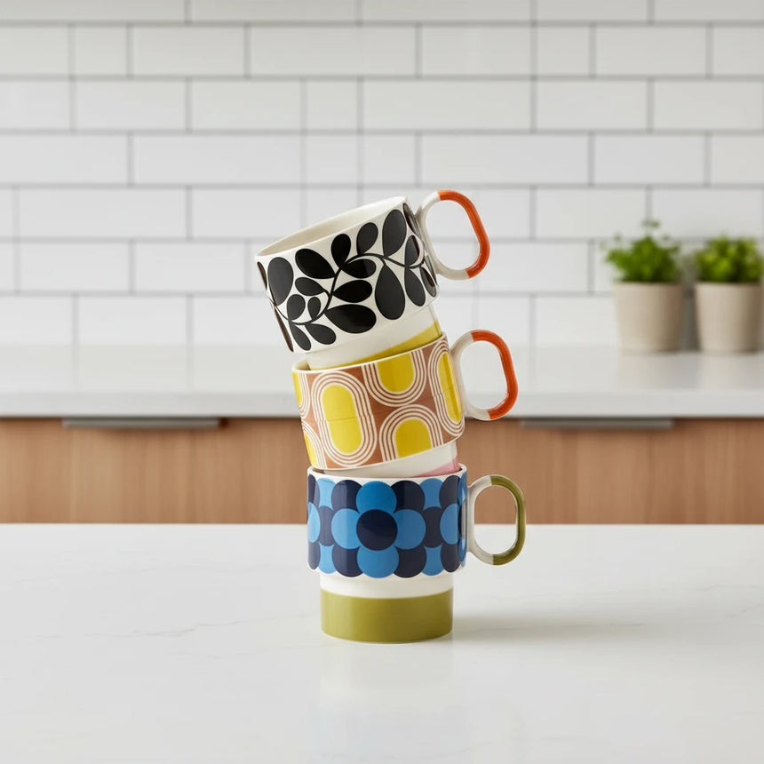 Four colorful mugs with patterned designs on a light beige background