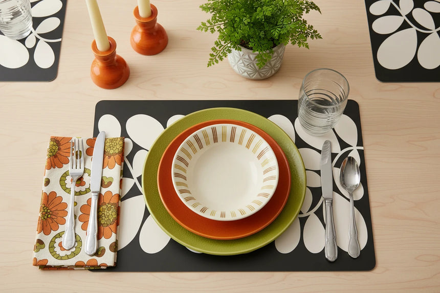 Decorative black placemat with white leaf pattern on a beige background