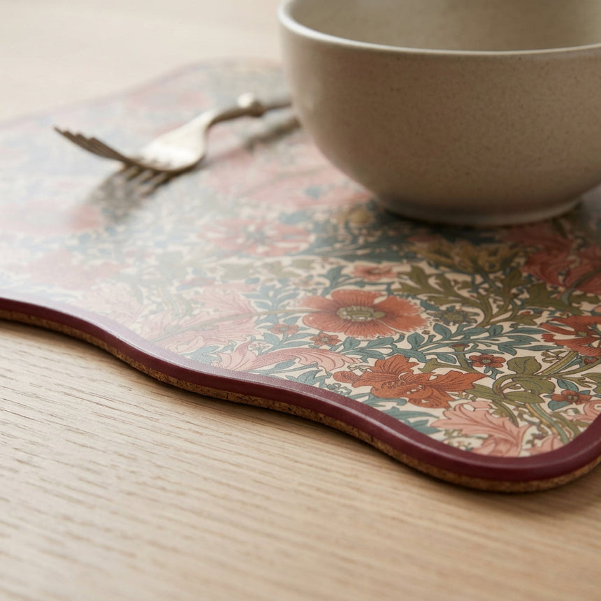 A rectangular decorative mat with a vintage floral pattern in muted tones of terracotta, sage green, and beige, finished with a dark red border, shown on a plain white background.