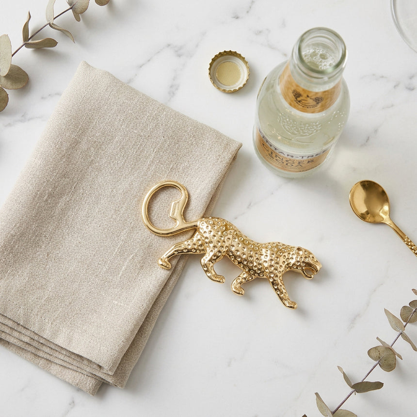 A gold leopard-shaped bottle opener with a textured surface , shown on a plain white background.