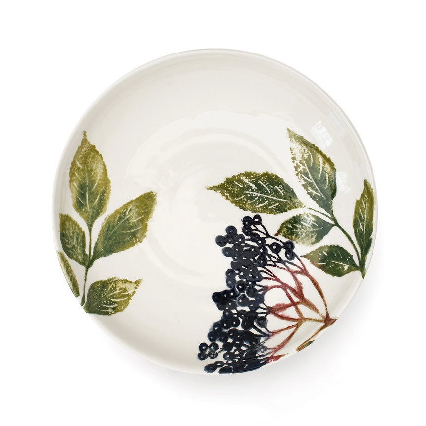 Round ceramic plate with leaf and berry design on a white background