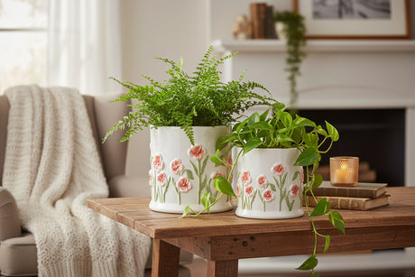 Two white ceramic planters with floral designs on a white background