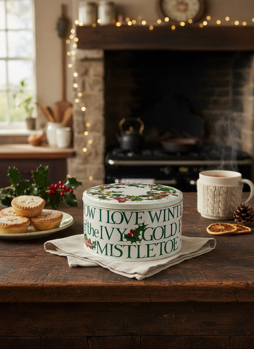 Decorative Christmas-themed cake tin  with text and holly design on a white background