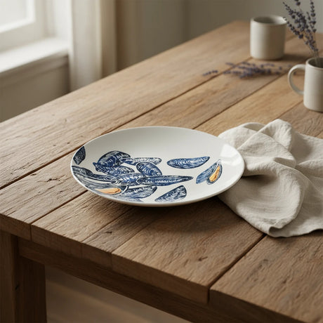 Ceramic plate with blue mussel shell design on a white background