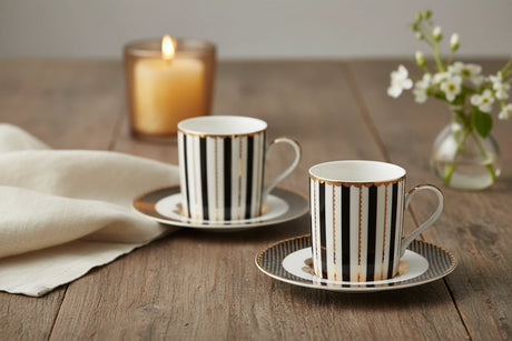 Two black and gold striped ceramic cups with saucers on a white background