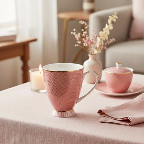 Pink mug with gold polka dot pattern on a white background
