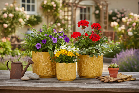 Set of three mustard yellow ceramic planters with floral patterns on a white background