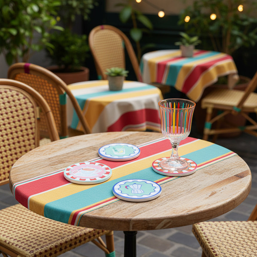 Set of colorful coasters with illustrations on a yellow and white striped tablecloth.