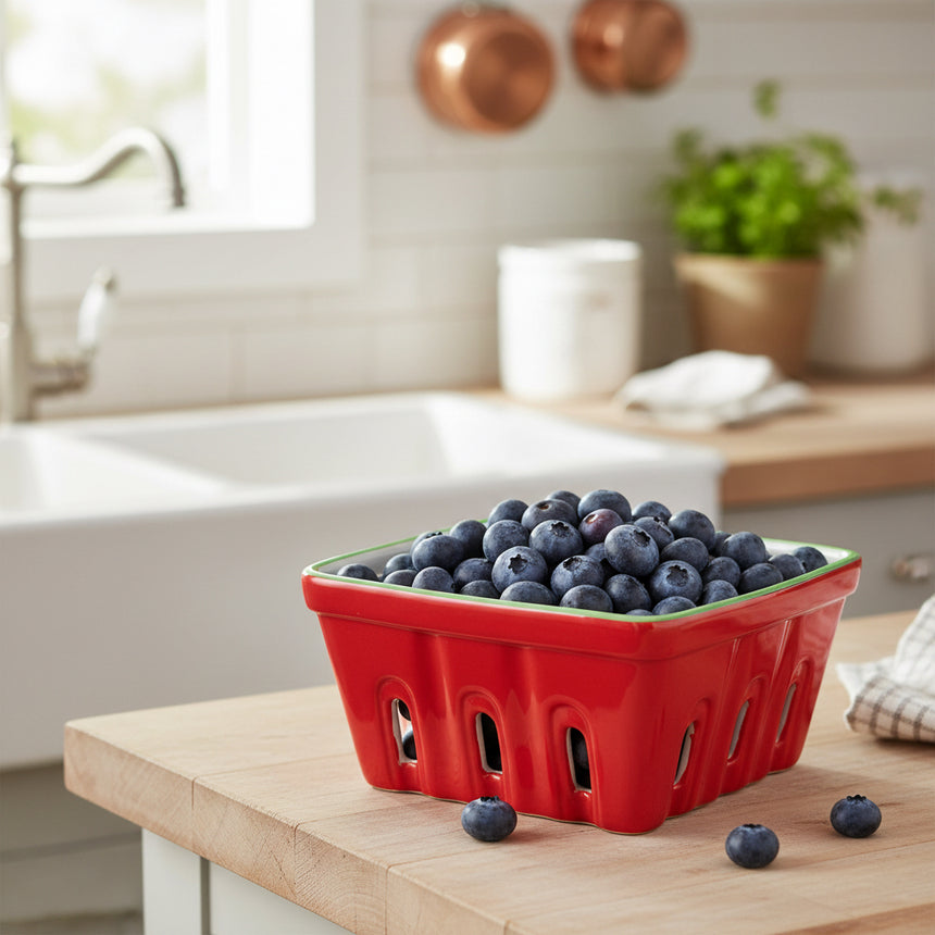 Red berry basket with green rim on a white background