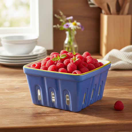 Blue ceramic berry basket with yellow rim on a white background