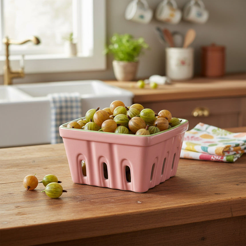 Pink ceramic basket with green rim on a white background