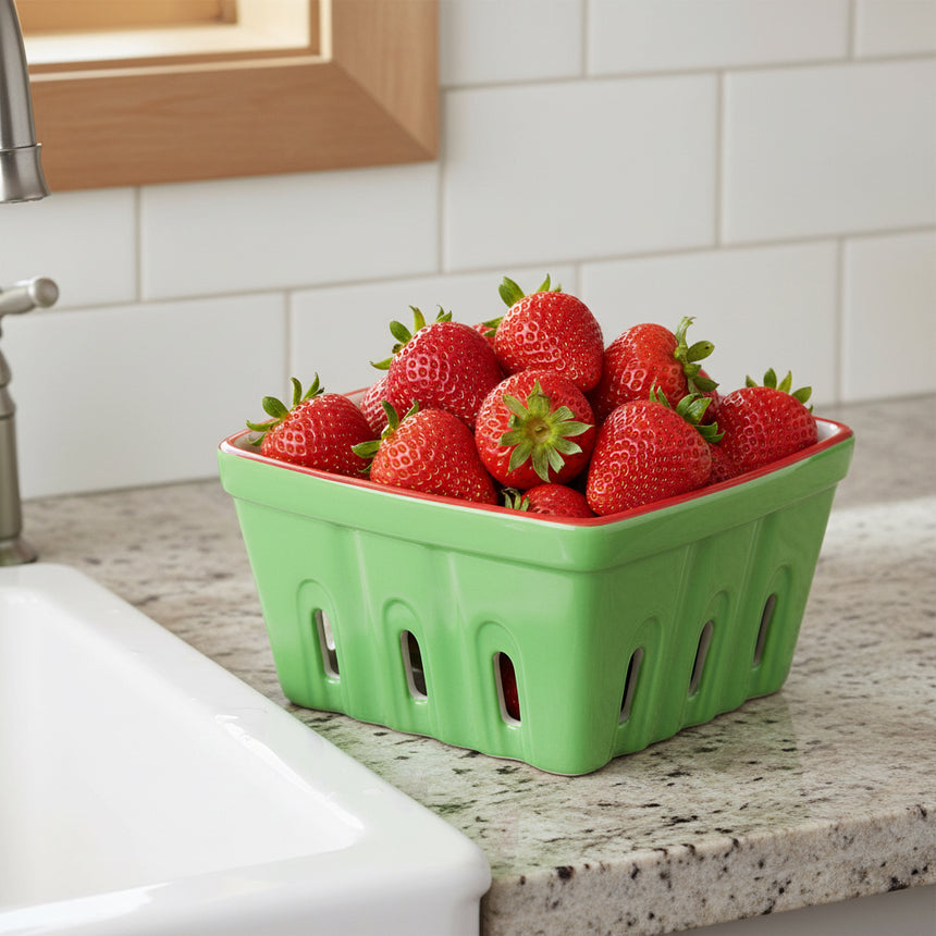 Green ceramic punnet with red rim on a white background
