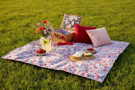 Roll-up picnic blanket with floral pattern and red strap on a white background