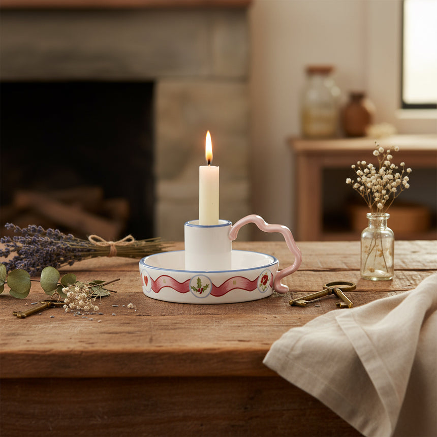Decorative ceramic candle holder  with floral design and pink handle on a white background