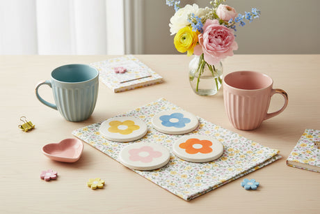 Four round coasters  with colorful flower designs on a white background