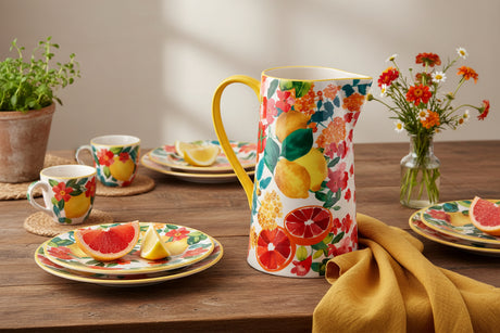 Decorative pitcher with floral and fruit design on a white background