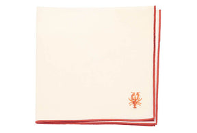 Beige napkin with red border and embroidered lobster design on a white background
