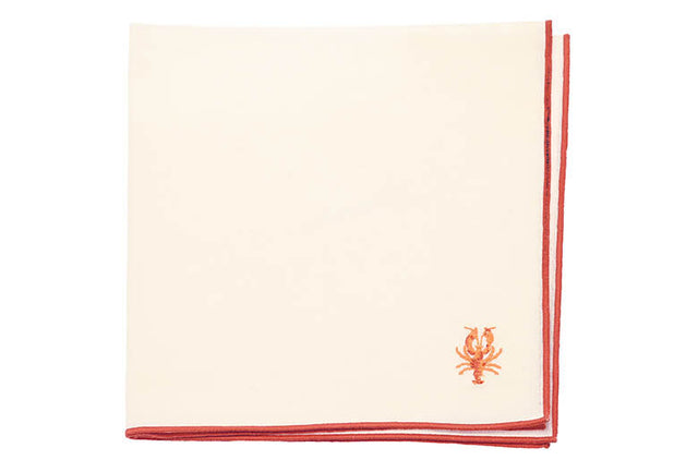 Beige napkin with red border and embroidered lobster design on a white background