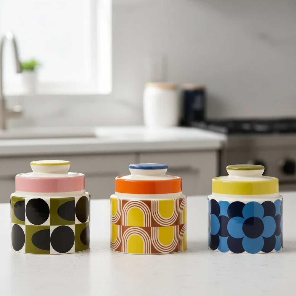 Three ceramic jars with colorful geometric patterns on a beige background