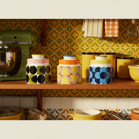 Three ceramic jars with colorful geometric patterns on a beige background