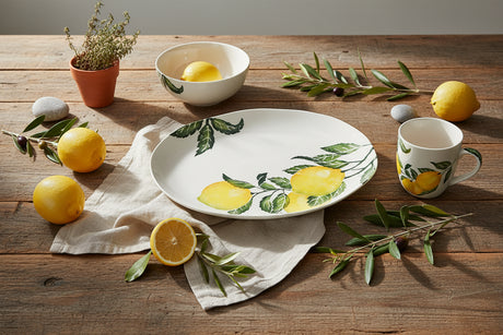 An oval white ceramic serving platter decorated with a watercolor-style print of yellow lemons on branches with green leaves, shown against a plain white background.