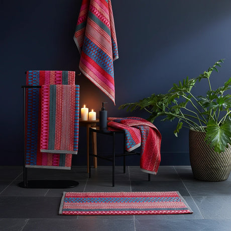 Colorful patterned towels and rug on a stand with a plant in the background