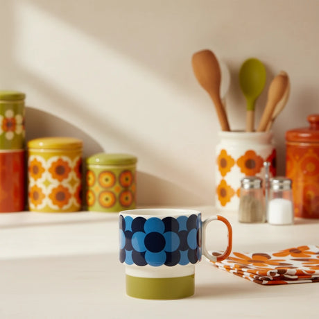 Colorful mug with blue pattern and orange handle on a beige background