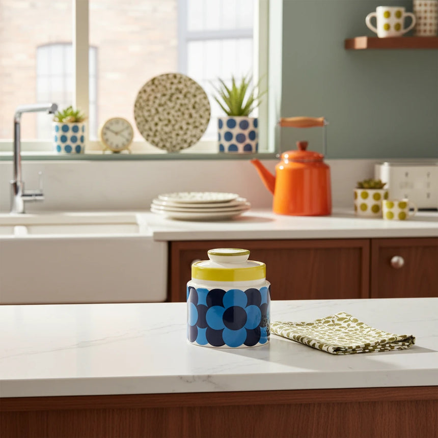 Decorative jar with blue floral pattern and yellow lid on a beige background